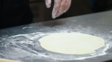 Mutfak. Düz hamur yapan bir adam.