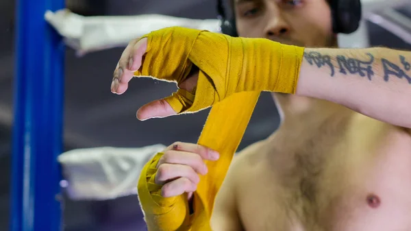 CAJA - boxeador con un tatuaje está vendando su brazo con un vendaje amarillo — Foto de Stock