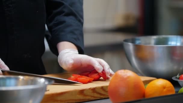 Koken in de moderne keuken - chef-kok snijdt kerstomaten op het bureau — Stockvideo