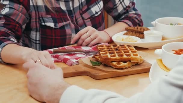 Una linda pareja desayunando tomados de la mano junto a la mesa — Vídeos de Stock