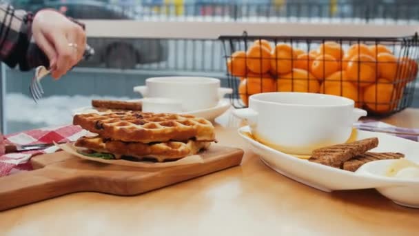 Bir çift öğle yemeği yiyor. Bir kadın waffle kesmeye başlıyor. — Stok video