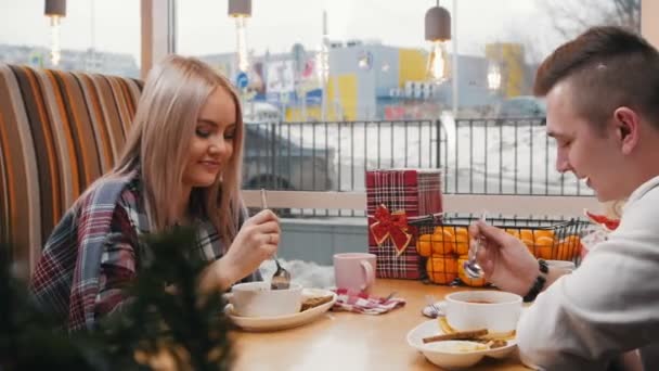 Una joven pareja en la cafetería comienza a comer su almuerzo — Vídeos de Stock