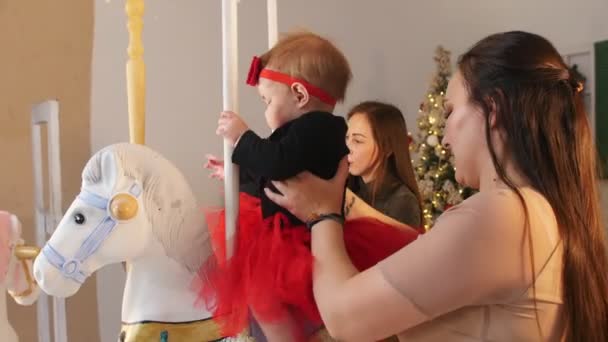 Weihnachtskonzept - zwei Babys mit ihren Müttern auf dem Karussell — Stockvideo