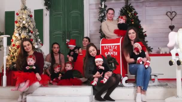 Conceito de Natal - várias mulheres mães segurando seus bebês em suas mãos em estúdio decorado — Vídeo de Stock