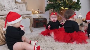 Noel konsepti - Halıda oturan küçük bebekler ve dekore edilmiş stüdyoda Noel oyuncaklarıyla oynuyorlar