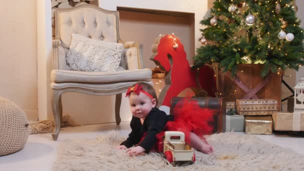 Noel konsepti - küçük gülümseyen bir kız bebek oyuncak bir arabayla oynuyor. — Stok video
