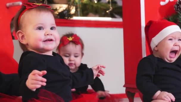 Concepto de Navidad - Pequeños bebés sentados en la alfombra - uno de ellos llorando — Vídeos de Stock