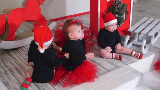 Koncepcja Bożego Narodzenia - Małe dzieci siedzące na podłodze i czekające na sesję zdjęciową — Wideo stockowe