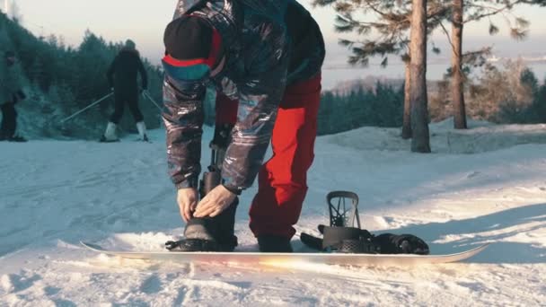 Snowboarden op de berg - Een man met een kunstbeen die in grote laarzen op het bord stapt — Stockvideo