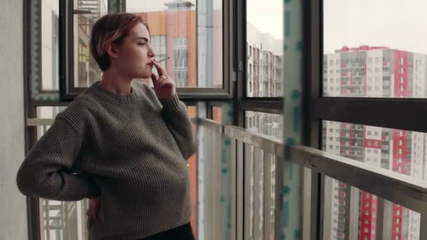 Těhotná kouřící žena stojící na balkóně — Stock video