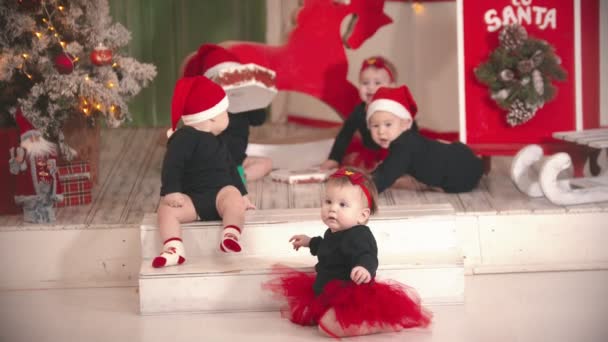 Koncepcja Bożego Narodzenia - Małe dzieci siedzące na dywanie i bawiące się pustym pudełkiem — Wideo stockowe