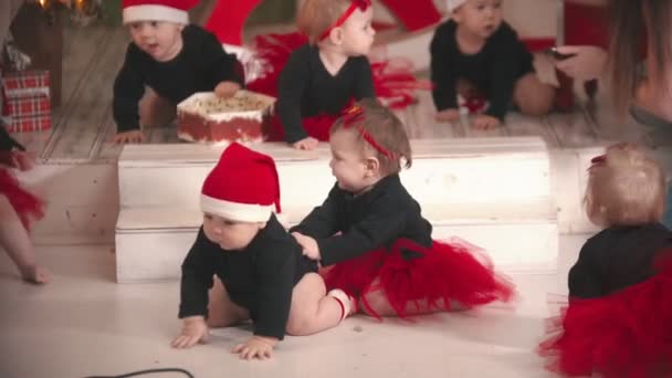 Concepto de Navidad - Pequeños bebés sentados en el suelo en el estudio de Navidad — Vídeos de Stock