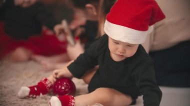 Stüdyoda Noel süslemeleri - küçük bebek oğlan ve kız halının üzerinde oyuncaklarla oynuyorlar