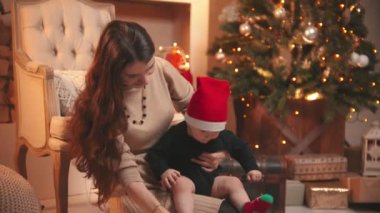 Yeni yıl stüdyosunda bebeğiyle oynayan gülümseyen genç bir kadın.