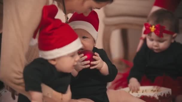 Weihnachtsdekoration im Atelier - kleine Babys spielen mit Weihnachtsspielzeug — Stockvideo