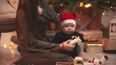 Noel konsepti - küçük bebeğiyle Noel stüdyosunda oynayan genç bir kadın - oyuncak geyik tutan bir bebek
