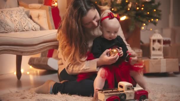 Concepto de Navidad - Una mujer jugando con su pequeña hija con una bola de Navidad — Vídeos de Stock