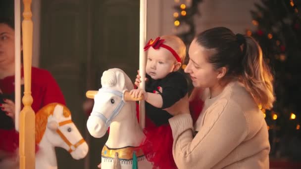 Julkoncept - leende mamma i beige tröja med sitt barn i julateljé — Stockvideo