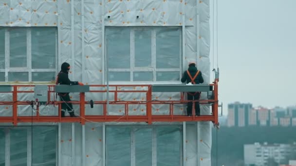 Два рабочих поднимаются на здание для продолжения строительства — стоковое видео