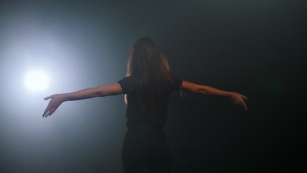 Jeune femme marchant vers la lumière dans un studio sombre 