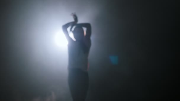 Silhouette einer jungen Frau, die im dunklen Studio mit ihren Händen tanzt — Stockvideo