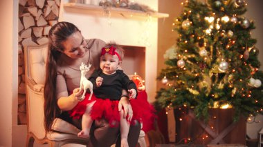 Küçük kızıyla oynayan gülümseyen genç bir kadın.