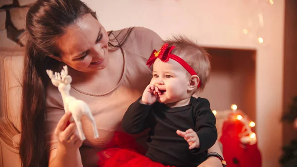 Christmas concept - A young happy woman sitting in chair with her little daughter in christmas studio — ストック写真