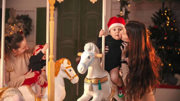 Having fun with christmas decoration - a woman kiss her baby son in the cheek — ストック写真