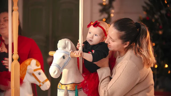 Concepto de Navidad - madre sonriente en jersey beige con su bebé en el estudio de Navidad — Foto de Stock