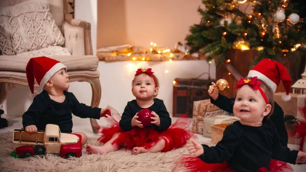 Christmas decorations in the studio - little babies playing with christmas toys indoors — ストック写真