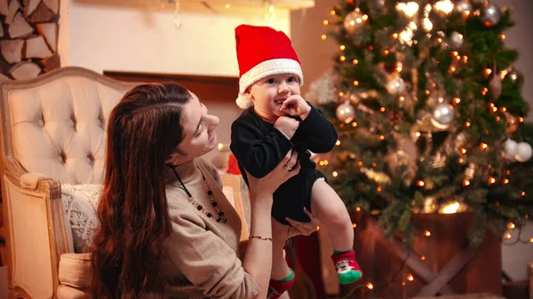 Estudio decorado de Navidad - joven mujer sonriente jugando con su pequeño bebé — Foto de Stock