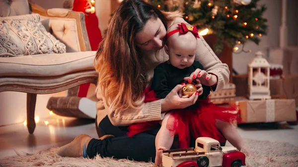 Navidad - Una mujer jugando con su pequeña hija con una bola de Navidad — Foto de Stock