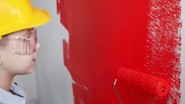 Un niño pintando una pared clara con pintura roja — Vídeo de stock