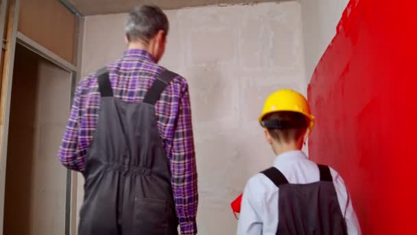 Ein Mann und ein kleiner Junge streichen Wände in einer neuen Wohnung — Stockvideo