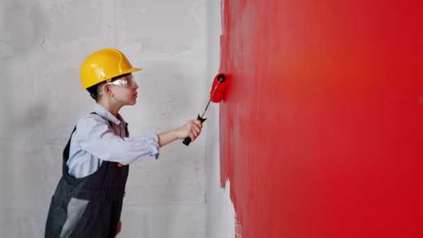 Appartement renovatie - een kleine jongen schilderen muur in rood — Stockvideo