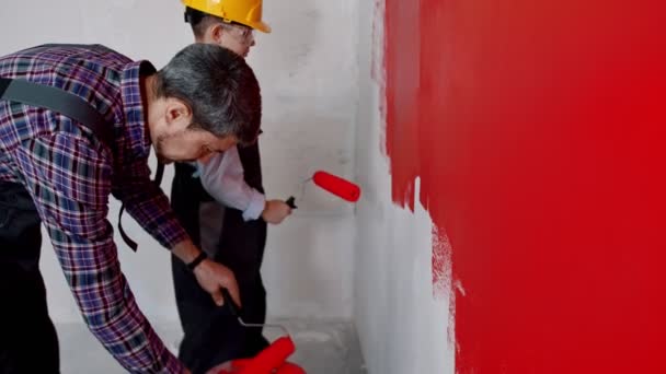 Apartment renovation - father and son covering roller in red paint — Stock Video