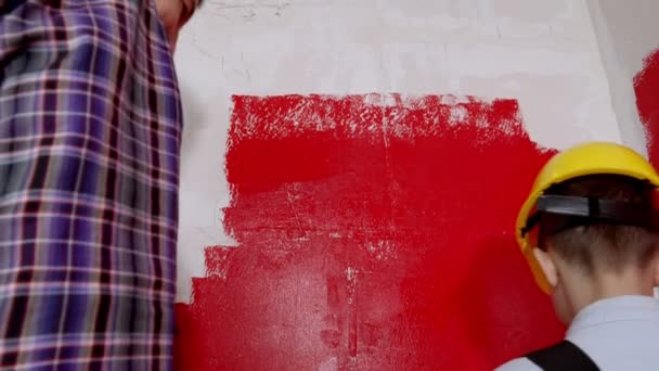 Familia reparar el apartamento - niño y su padre pintando la pared en color rojo — Vídeo de stock