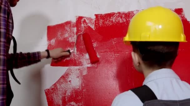 Familia feliz reparar el apartamento - niño y su padre pintando la pared en color rojo — Vídeo de stock