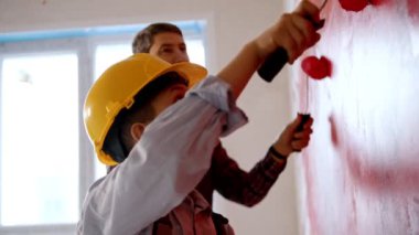Aile daireyi onarıyor. Küçük çocuk ve babası duvarları kırmızıya boyuyor ve birbirlerine saygı gösteriyorlar.