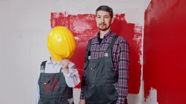 Mały chłopiec i jego ojciec malują ściany - chłopiec zakłada hełm — Wideo stockowe