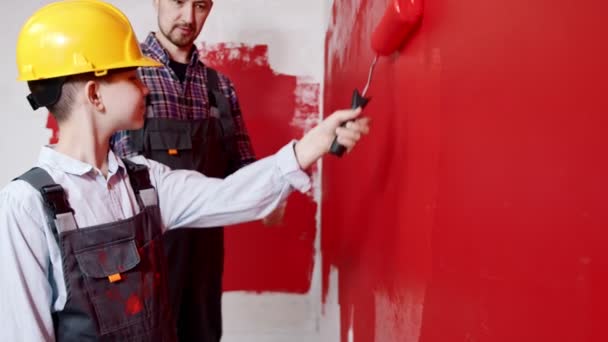 Happy family repair the apartment - father explains his son how to correctly paint walls — 비디오