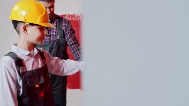 Een kleine jongen schilderen muur in rode kleur - zijn vader trots op hem — Stockvideo
