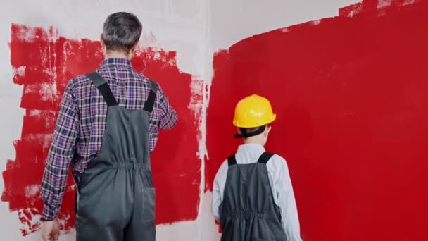 Un niño pequeño y su padre pintando paredes abrazando y sonriendo — Vídeos de Stock