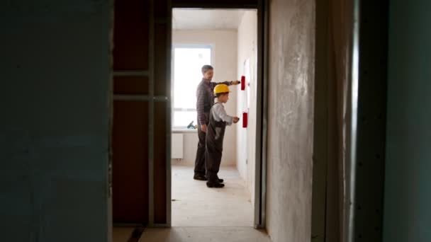 Reparación familiar proyecto de apartamento - niño y su padre pintando la pared en color rojo — Vídeos de Stock