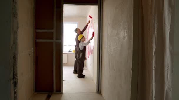 Repairing draft apartment - little boy and his father painting walls inside the room — Stock Video