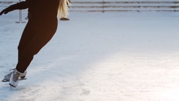 Een jonge blonde vrouw schaatst op de ijsbaan — Stockvideo