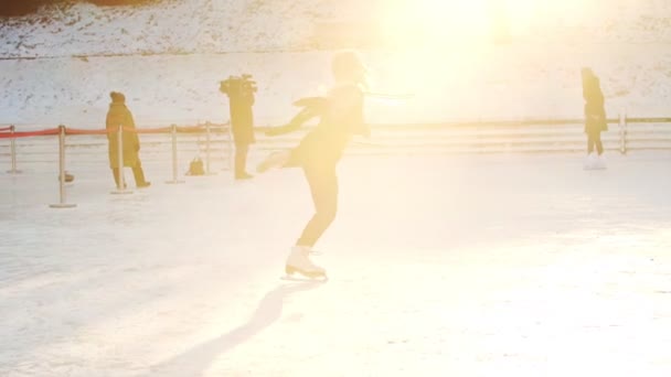 Een jonge blonde vrouw figuur schaatser draaien rond zichzelf op de ijsbaan — Stockvideo