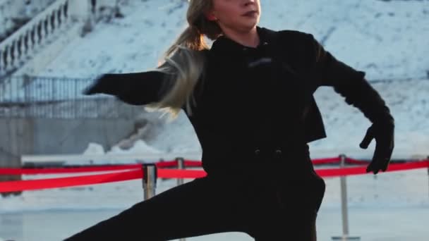 Μια νεαρή γυναίκα φιγούρα σκέιτερ γυρίζει γύρω από τον εαυτό της σε παγοδρόμιο στην ύπαιθρο — Αρχείο Βίντεο