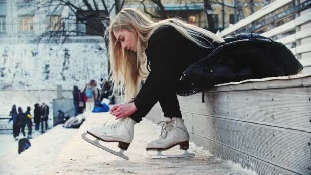 Eine junge blonde Frau schnürt ihre Eiskunstlaufschuhe — Stockvideo
