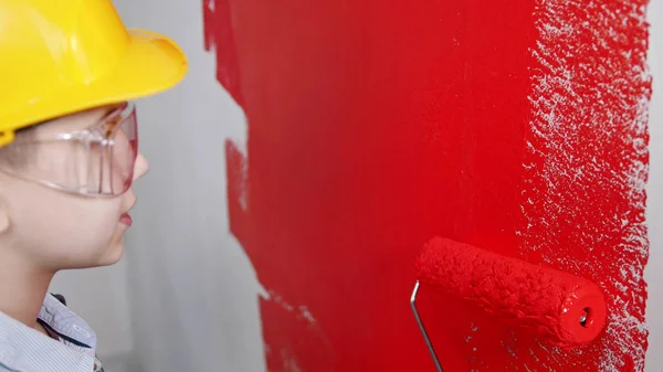 Een jongetje schilderend doorzichtig muur met rode verf — Stockfoto